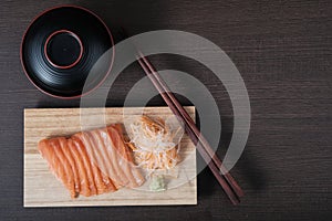 Top view raw salmon sashimi on wood board, chopsticks, and soup