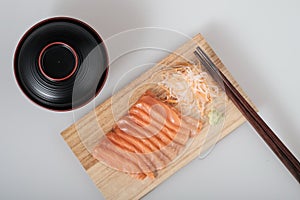 Top view raw salmon sashimi on wood board, chopsticks, and soup