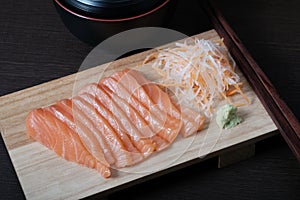 Top view raw salmon sashimi on wood board, chopsticks, and soup