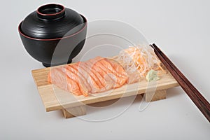 Top view raw salmon sashimi on wood board, chopsticks, and soup