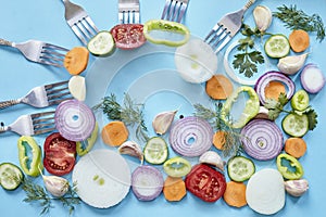 Top view of raw, sliced spices and vegetables on forks against a blue background