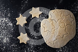 Top view of raw star shaped cookies over black background