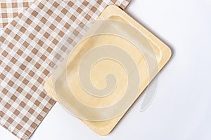Top view of rectangular wooden dishes with plate on napkin on white table, template, copy space