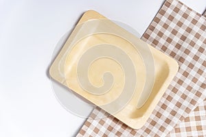 Top view of rectangular wooden dishes with plate on napkin on white table, template, copy space