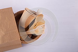 Top view on recycling paper cups, wooden fork, spoon in brown eco bag on white table. Copy space for text, top view, flat lay