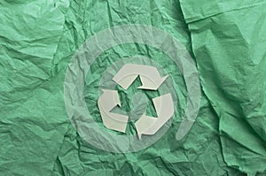 Top view of recycling symbol on the torn green paper.Empty space for design photo