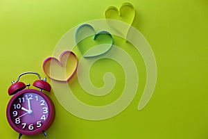 Top view of Red alarm clock with Heart ribbon on yellow paper background,concept Heart day and mother day background