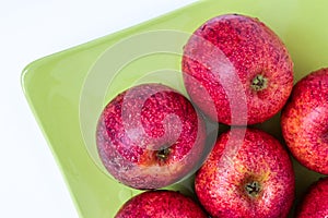 Top view of red apples of pero bravo esmolfe species washed with fresh water on a green plate