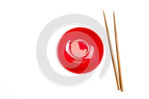 Top view of red bowl with wooden chopsticks on a white background. Isolated background