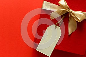 Top view on red Christmas gift box decorated with ribbon on red paper background.