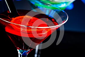 Top of view of red cocktail with blue light disco background with space for text