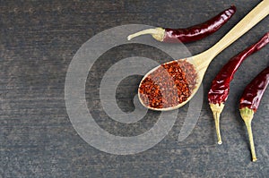 Top view red dried crushed hot chili peppers and chili flakes or powder in wooden spoon and bowl