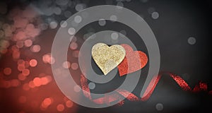 Top view of red and golden hearts with ribbon, black background, bokeh