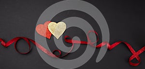 Top view of red and golden hearts with ribbon, black background, isolated, banner