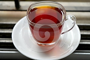TOP VIEW OF RED LIQUOR TEA IN TRANSPARENT CUP AND PLATE IN WINDOW photo