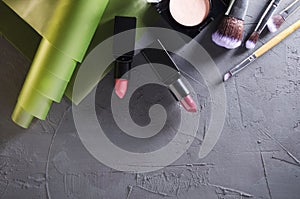 Top view of cosmetic products.Lipsticks, blush, professional brushes on the dark grey surface.Empty space for text