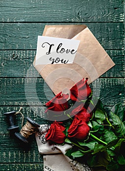 top view of red roses and envelope with I love you valentine card