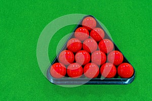 Top view 15 red snooker balls in a black frame on a green velvet snooker table