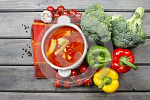 Top view of red tomato soup on wooden table. Fresh vegetables ar