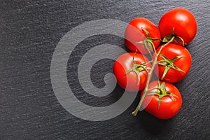 top view of red tomatoes on black slate background, cl