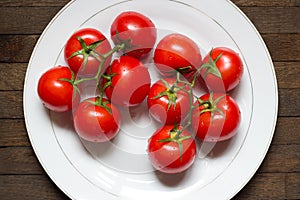 Top view of red washed tomatoes on big white plate