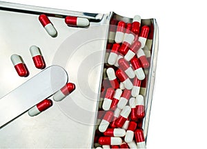 Top view of red, white antibiotic capsules pills isolated on stainless steel drug tray with clipping path, drug resistance concept