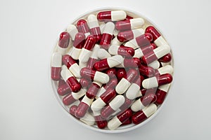 Top view of red, white, capsule pills in plastic container