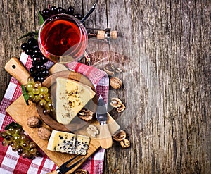 Top view of red wine, grape and cheese on rustic wooden table background with copyspace. French cuisine product from above