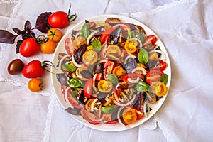 Top view of red & yellow cherry and plum tomato salad with basil leaves