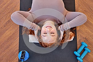 Top View On Redhead Woman listening to music after sport, yoga exercises, relaxation