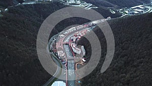 Top view of resort town with river in mountains. Mountain resort town is located on river in forest area with cable cars