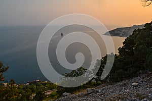 top view of resort town on shore of Black Sea bay among mountains and rocks, blue water, summer, bushes and trees