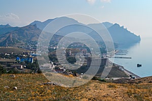 top view of resort town on shore of Black Sea bay among mountains and sharp rocks, blue water, summer