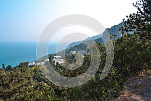 Top view of resort town with white buildings on coast of Black Sea bay among mountains, blue water, summer, green forest, trees