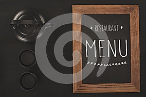 top view of restaurant menu in wooden frame and tea set