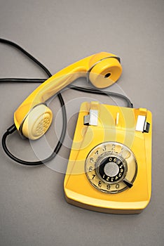 top view of retro and yellow telephone on grey background.