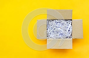 Top view of reuse shredded paper documents in brown paper cardboard isolated on yellow background with copy space, flat lay