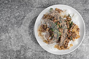 Top view Rice topped with stir-fried beef and holy basil Pad Ka Prao popular Thai street food on the concrete table