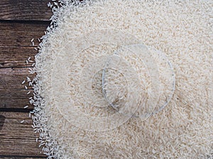 Top view rice in a white bowl and scattered near on wooden table with copy space for text and design