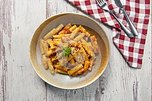 Top view of rigatoni pasta with arrabiata sauce on a white wooden table