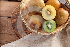 Top view ripe golden kiwi fruit and green kiwi fruit in wood basket on wooden table background. Healthy fruits concept