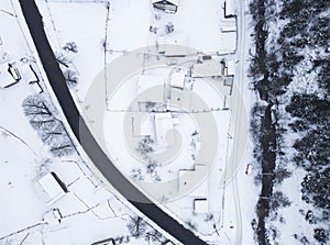 Top view of the road near the snow-covered houses and the mountain river flowing near them