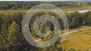 Top view of roads passing by river with trees in autumn. Clip. Beautiful autumn landscape with forest near muddy river