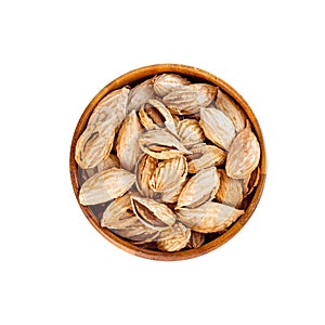 Top view of roasted brown almond nuts in cracked shell in wooden bowl isolated on white background.