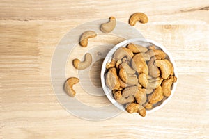 Top view roasted golden cashew nuts on white bowl healthy food protein-rich