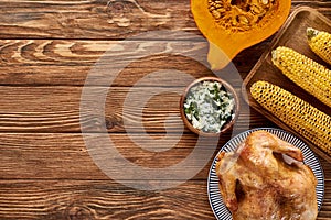 Top view of roasted turkey, pumpkin and grilled vegetables served on wooden table.