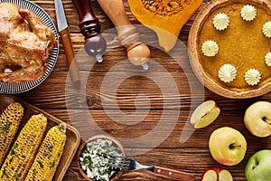 Top view of roasted turkey, pumpkin pie and grilled vegetables served on wooden table.