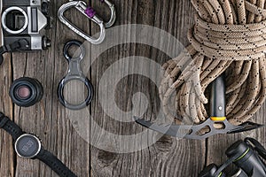 Top view of rock climbing equipment on wooden background. Chalk bag, rope, climbing shoes, belay/rappel device, carabiner and asce