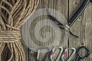 Top view of rock climbing equipment on wooden background. Chalk bag, rope, climbing shoes, belay/rappel device, carabiner and asce