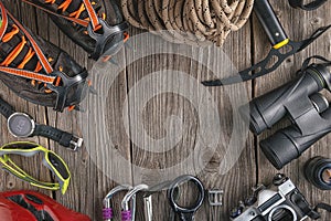 Top view of rock climbing equipment on wooden background. Chalk bag, rope, climbing shoes, belay/rappel device, carabiner and asce